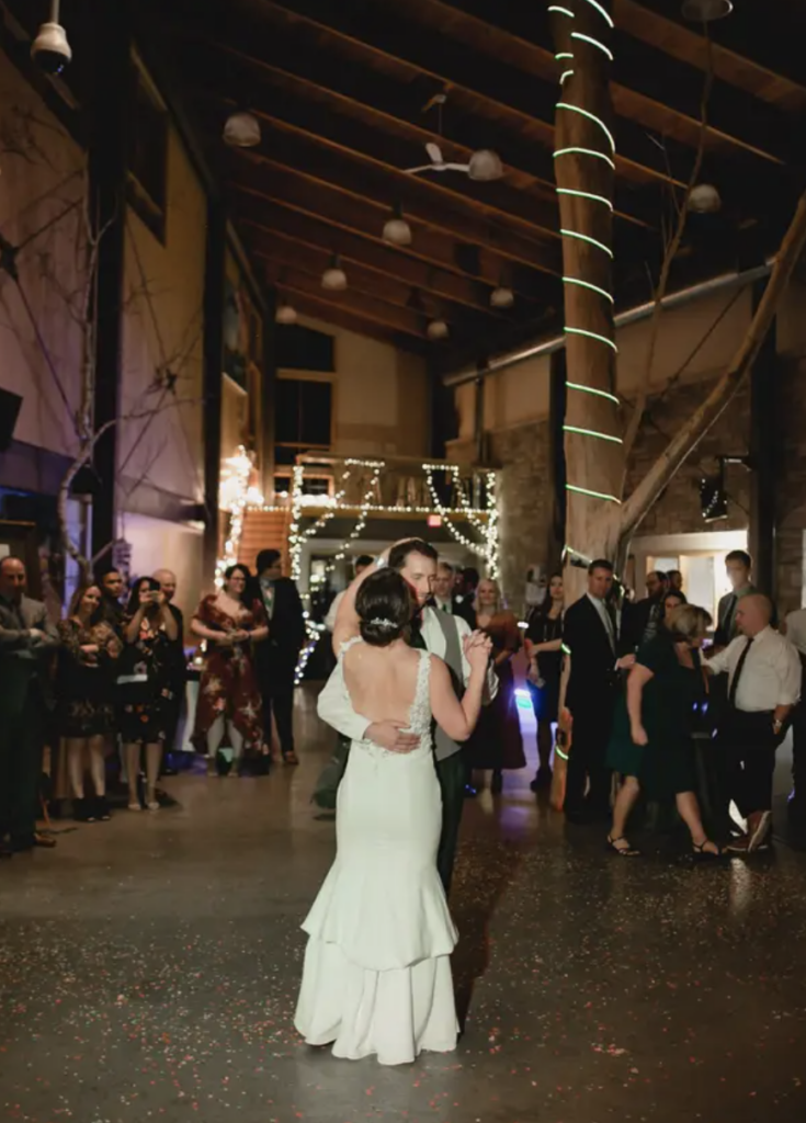 A bride and groom share their first dance in a dimly lit space of their wedding venue: The Nature Place.